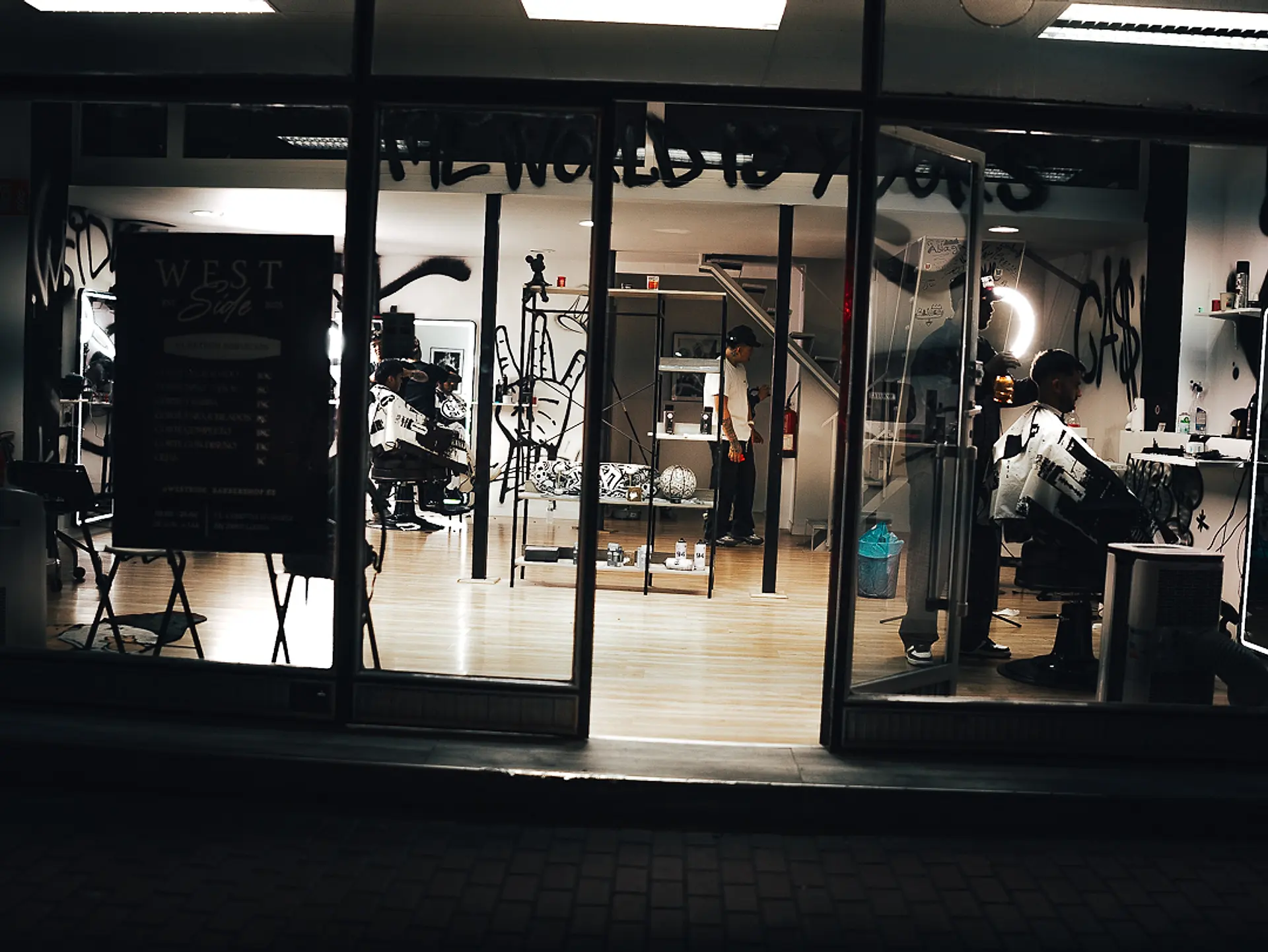 Fachada de WestSide Barbershop de noche